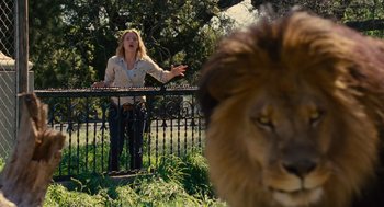 Movie still from “We Bought a Zoo” (2011), directed by Cameron Crowe – A woman standing next to a lion behind a metal fence; Wide shot, Low angle