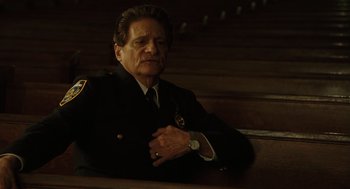 Movie still from “We Own the Night” (2007), directed by James Gray – A man sitting on a wooden bench wearing a uniform; Medium shot, Low angle