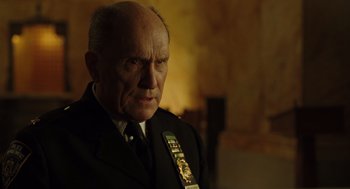 Movie still from “We Own the Night” (2007), directed by James Gray – An older man wearing a suit and tie; Close Up shot, Low angle