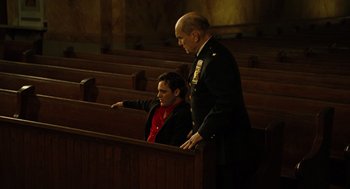 Movie still from “We Own the Night” (2007), directed by James Gray – A man and a woman standing next to each other in pews; Medium shot, Low angle