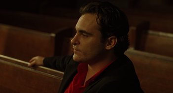 Movie still from “We Own the Night” (2007), directed by James Gray – A man in a red shirt sitting in a chair; Close Up shot, Over the shoulder angle