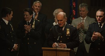 Movie still from “We Own the Night” (2007), directed by James Gray – A group of men standing around a podium; Medium shot, Over the shoulder angle