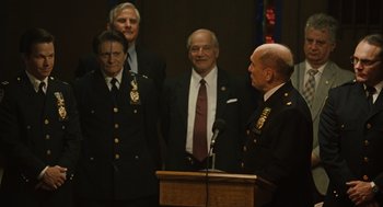 Movie still from “We Own the Night” (2007), directed by James Gray – A group of men standing in front of a podium; Medium shot, Over the shoulder angle