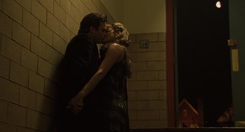 Movie still from “We Own the Night” (2007), directed by James Gray – A man and a woman kissing near a brick wall; Medium shot, Low angle