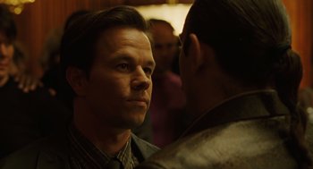 Movie still from “We Own the Night” (2007), directed by James Gray – A man looking at another man in front of a group of people; Close Up shot, Over the shoulder angle