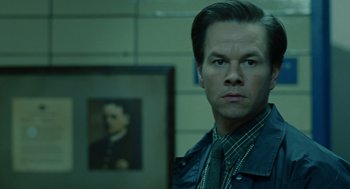 Movie still from “We Own the Night” (2007), directed by James Gray – A man standing in front of a picture of himself; Close Up shot, Low angle