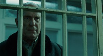 Movie still from “We Own the Night” (2007), directed by James Gray – An old man looking out of a jail cell; Close Up shot, Low angle