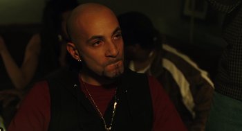 Movie still from “We Own the Night” (2007), directed by James Gray – A man with a bald head wearing a red shirt and a black vest; Close Up shot, Over the shoulder angle