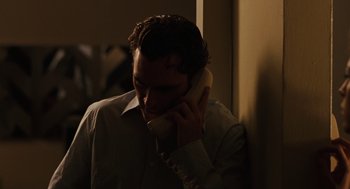 Movie still from “We Own the Night” (2007), directed by James Gray – A man talking on a phone while standing in a room; Close Up shot, High angle