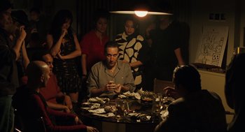 Movie still from “We Own the Night” (2007), directed by James Gray – A group of people sitting around a dinner table; Medium shot, High angle