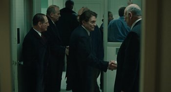 Movie still from “We Own the Night” (2007), directed by James Gray – A group of men in suits shaking hands; Medium shot, Over the shoulder angle