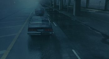 Movie still from “We Own the Night” (2007), directed by James Gray – A couple of cars driving down a wet street; Wide shot, High angle