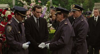 Movie still from “We Own the Night” (2007), directed by James Gray – A group of men standing next to each other in front of flowers; Medium shot, Over the shoulder angle