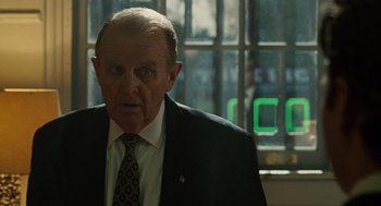 Movie still from “We Own the Night” (2007), directed by James Gray – An older man wearing a suit and tie in front of a window; Close Up shot, Over the shoulder angle