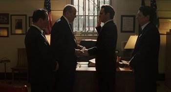 Movie still from “We Own the Night” (2007), directed by James Gray – Two men in business suits and one man is holding his hand up to his face; Medium shot, Low angle