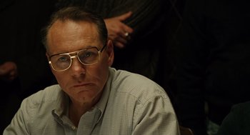 Movie still from “We Own the Night” (2007), directed by James Gray – A person wearing glasses and a plaid shirt; Close Up shot, Over the shoulder angle