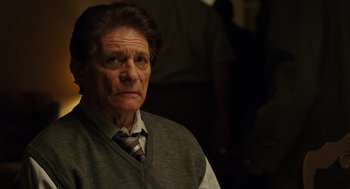 Movie still from “We Own the Night” (2007), directed by James Gray – An older man wearing a vest and a tie; Close Up shot, Over the shoulder angle