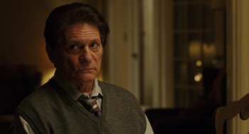 Movie still from “We Own the Night” (2007), directed by James Gray – An older man wearing a vest and a tie; Close Up shot, Over the shoulder angle