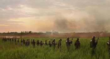 Movie still from “We Own the Night” (2007), directed by James Gray – A group of people standing in a field with smoke billowing in the background; Extreme Wide shot, High angle