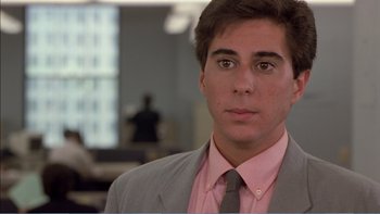 Movie still from “Weekend at Bernie's” (1989), directed by Ted Kotcheff – A man in a suit and pink shirt is looking at the camera; Close Up shot, Over the shoulder angle