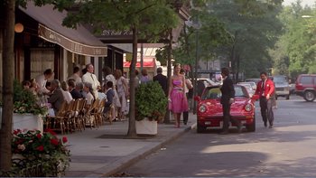 Movie still from “Weekend at Bernie's” (1989), directed by Ted Kotcheff – A group of people standing on a sidewalk near a tree; Wide shot, Over the shoulder angle