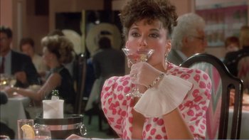 Movie still from “Weekend at Bernie's” (1989), directed by Ted Kotcheff – A woman holding a wine glass in her hand; Medium shot, Over the shoulder angle