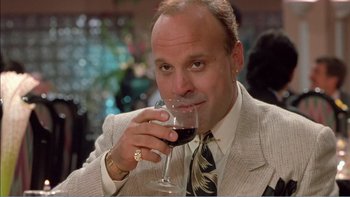 Movie still from “Weekend at Bernie's” (1989), directed by Ted Kotcheff – A man in a suit drinking a glass of red wine; Close Up shot, Low angle