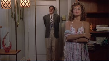 Movie still from “Weekend at Bernie's” (1989), directed by Ted Kotcheff – A man and a woman standing next to each other in front of a mirror; Medium shot, Over the shoulder angle