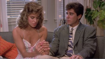 Movie still from “Weekend at Bernie's” (1989), directed by Ted Kotcheff – A man and a woman sitting next to each other on a couch; Medium shot, Over the shoulder angle