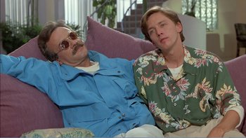 Movie still from “Weekend at Bernie's” (1989), directed by Ted Kotcheff – Two men laying on a purple couch next to each other; Medium shot, High angle