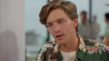 Movie still from “Weekend at Bernie's” (1989), directed by Ted Kotcheff – A young man with long brown hair wearing a floral shirt; Close Up shot, Over the shoulder angle
