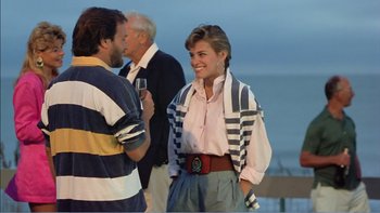 Movie still from “Weekend at Bernie's” (1989), directed by Ted Kotcheff – A man and a woman standing next to each other on the beach; Medium shot, Over the shoulder angle