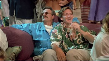 Movie still from “Weekend at Bernie's” (1989), directed by Ted Kotcheff – A couple of men sitting next to each other on top of a couch; Medium shot, High angle