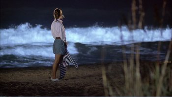 Movie still from “Weekend at Bernie's” (1989), directed by Ted Kotcheff – A woman walking on the beach at night; Wide shot, High angle