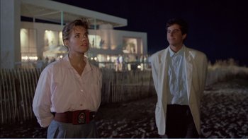 Movie still from “Weekend at Bernie's” (1989), directed by Ted Kotcheff – A man and a woman standing next to each other on the beach; Medium shot, Over the shoulder angle