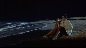 Movie still from “Weekend at Bernie's” (1989), directed by Ted Kotcheff – Two people sitting on the beach at night; Wide shot, High angle