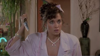 Movie still from “Weekend at Bernie's” (1989), directed by Ted Kotcheff – A person holding a cell phone in a room; Close Up shot, Over the shoulder angle