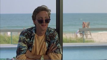 Movie still from “Weekend at Bernie's” (1989), directed by Ted Kotcheff – A person sitting in front of a pool with a view of the ocean; Medium shot, Low angle