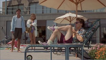 Movie still from “Weekend at Bernie's” (1989), directed by Ted Kotcheff – Two women are sitting on a bench under an umbrella; Wide shot, Low angle