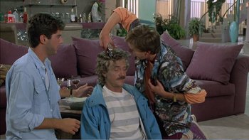 Movie still from “Weekend at Bernie's” (1989), directed by Ted Kotcheff – A group of people standing in a living room; Medium shot, Over the shoulder angle