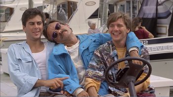 Movie still from “Weekend at Bernie's” (1989), directed by Ted Kotcheff – A group of young men sitting next to each other on a boat; Medium shot, High angle