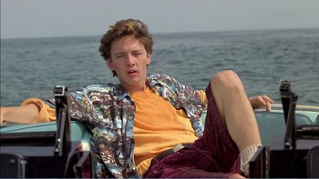 Movie still from “Weekend at Bernie's” (1989), directed by Ted Kotcheff – A young man sitting on a chair in front of the ocean; Medium shot, Low angle