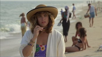 Movie still from “Weekend at Bernie's” (1989), directed by Ted Kotcheff – A woman in a straw hat is standing on the beach; Medium shot, Over the shoulder angle