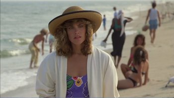 Movie still from “Weekend at Bernie's” (1989), directed by Ted Kotcheff – A woman in a straw hat standing on the beach; Medium shot, Over the shoulder angle