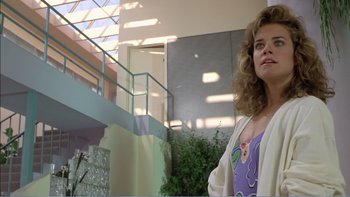 Movie still from “Weekend at Bernie's” (1989), directed by Ted Kotcheff – A woman standing in front of a staircase in a building; Medium shot, Low angle