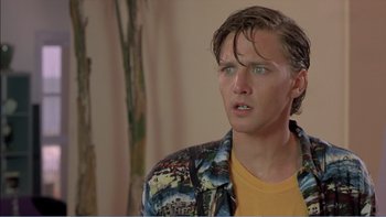 Movie still from “Weekend at Bernie's” (1989), directed by Ted Kotcheff – A young man with long brown hair wearing a yellow t - shirt; Close Up shot, Low angle