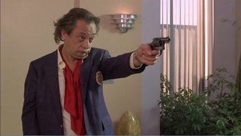 Movie still from “Weekend at Bernie's” (1989), directed by Ted Kotcheff – A man in a suit and tie holding a gun; Close Up shot, Low angle