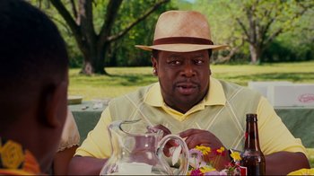 Movie still from “Welcome Home, Roscoe Jenkins” (2008), directed by Malcolm D. Lee – A man in a hat sitting at a table with a pitcher; Close Up shot, Over the shoulder angle