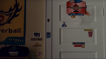 Movie still from “Welcome Home, Roscoe Jenkins” (2008), directed by Malcolm D. Lee – A white door with many stickers on it; Medium shot, Over the shoulder angle