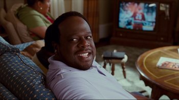 Movie still from “Welcome Home, Roscoe Jenkins” (2008), directed by Malcolm D. Lee – A man smiling for the camera while sitting in a chair; Close Up shot, High angle